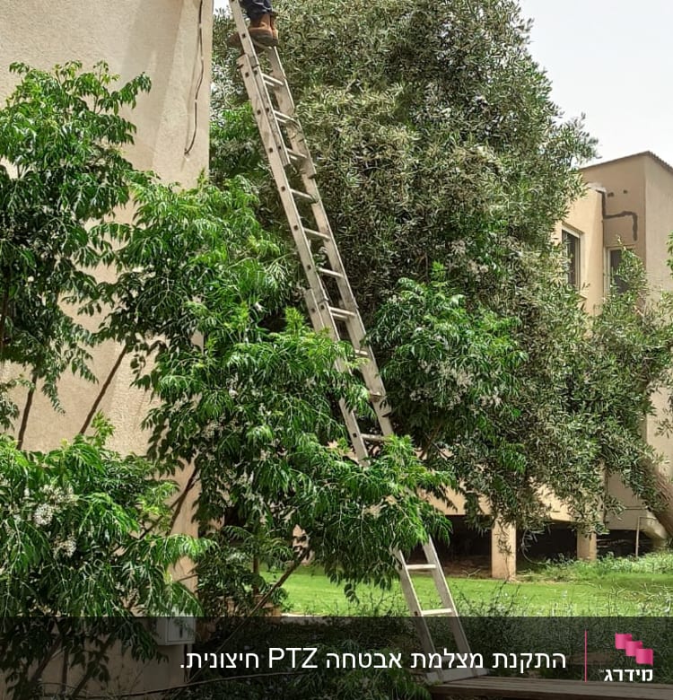 אדם מתקין מצלמת אבטחה על קיר בעזרת סולם